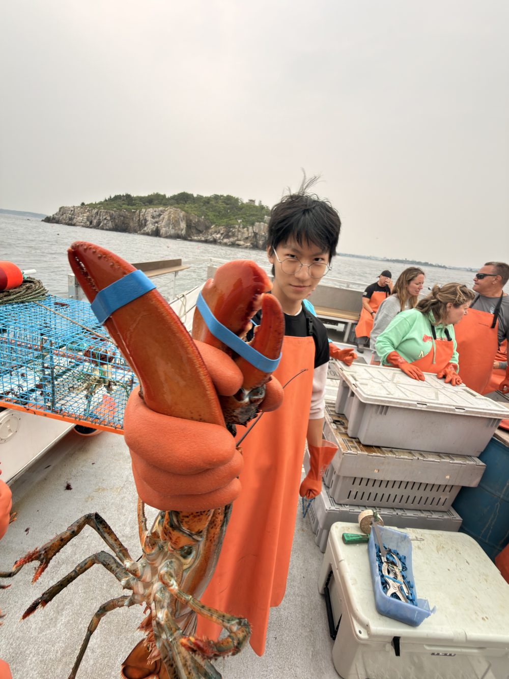 Tony Chen holding a lobster on a boat off the coast.